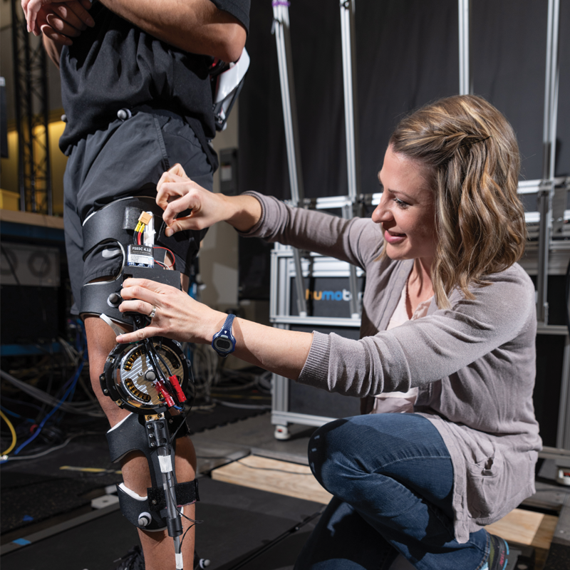 researcfher attaching a knee brace to a patient for testing