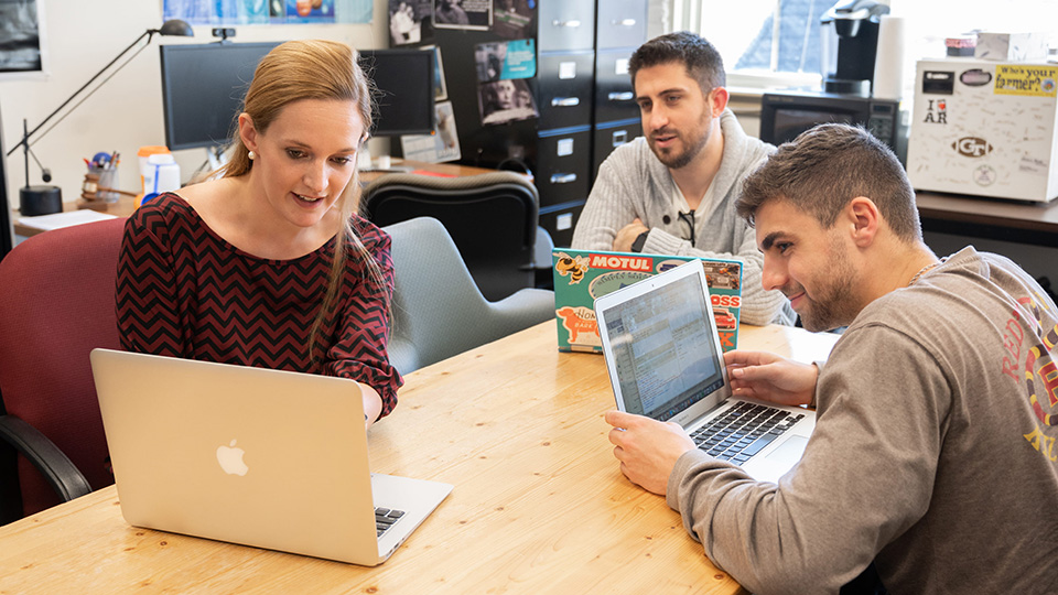 Teacher and students at a table watching a computer screen