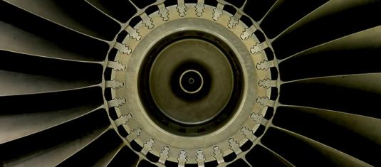 Close-up view of a jet engine turbine, showing fan blades and mechanical components used in aerospace systems.