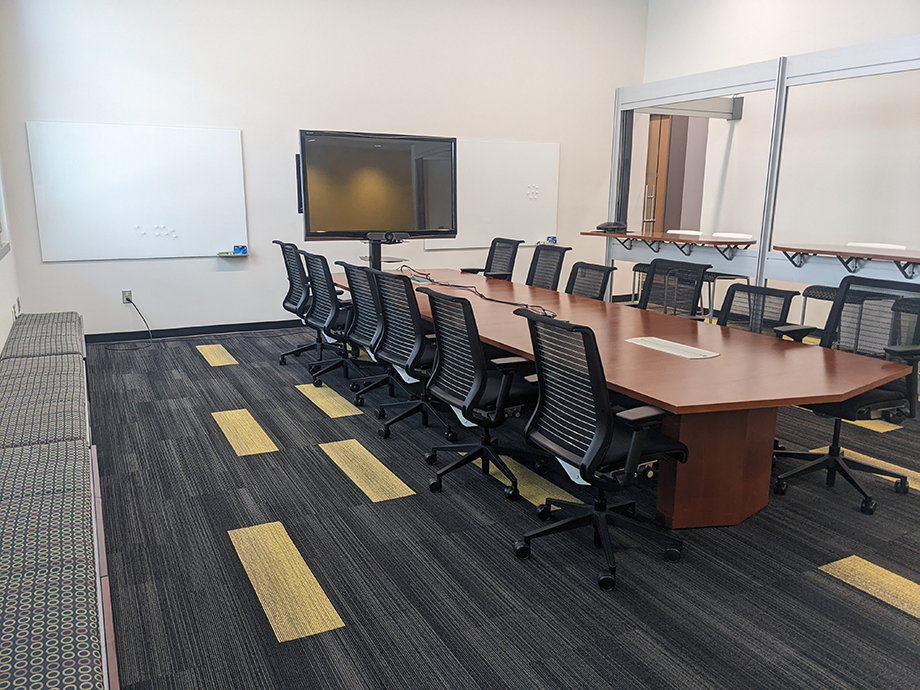 The Yellow Jacket Conference Room (TSRB 127) seats sixteen people total. There are twelve chairs at a large conference table. There is also seating for four at counter height chairs parallel to the table. On the other side of the table, there is bench seating. The room has audio-visual capabilities. Not shown is a long counter in the room (good for buffet/food service). 