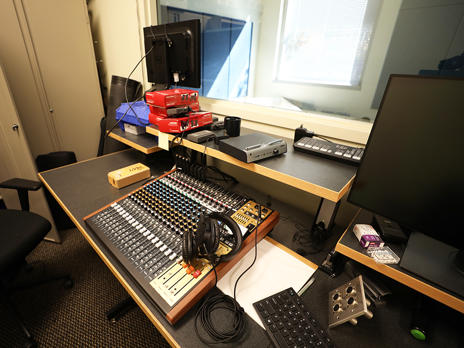 Audio production workspace with a mixing console, headphones, monitors, and recording equipment arranged on a desk in a usability lab.